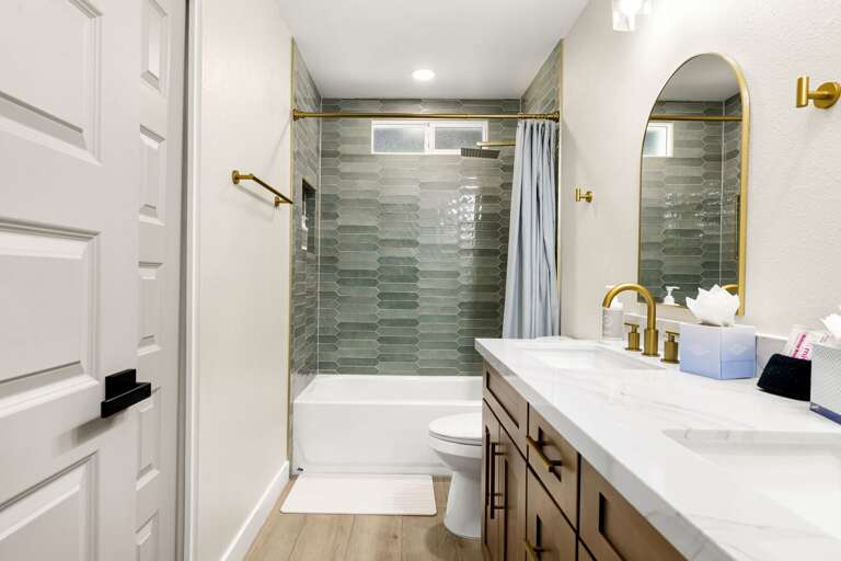 Bright and stylish bathroom featuring a large vanity, contemporary lighting, and a beautifully tiled shower.