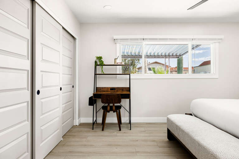 Clean and inviting bedroom with workspace, ample storage, and a relaxing atmosphere.