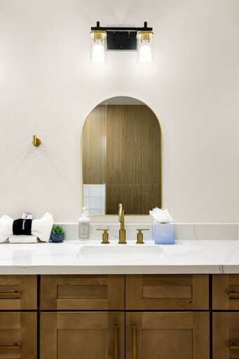 Elegant bathroom vanity featuring designer lighting, gold accents, and a sleek modern aesthetic.