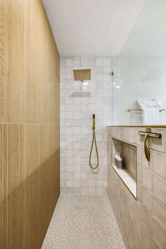 Luxurious walk-in shower with modern tilework, gold fixtures, and spa-inspired design details.