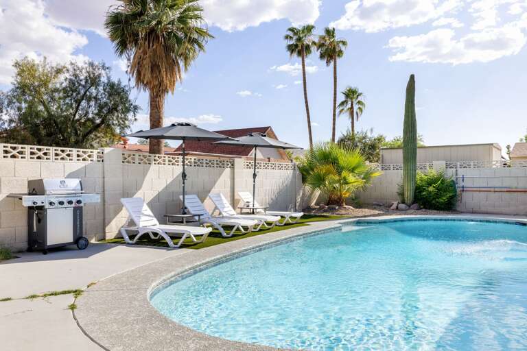 Private backyard pool with lounge chairs, sunny patio space, and tropical landscaping for the perfect outdoor escape.