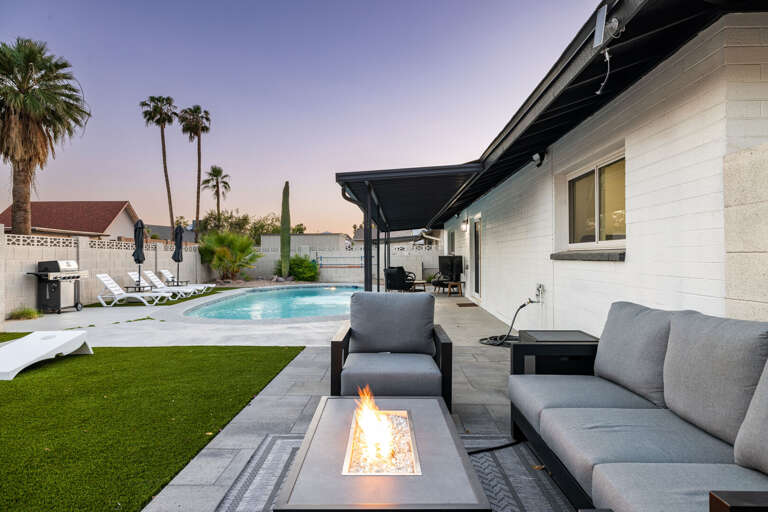 Relaxing outdoor lounge area with cozy seating, fire feature, and views of the private pool.