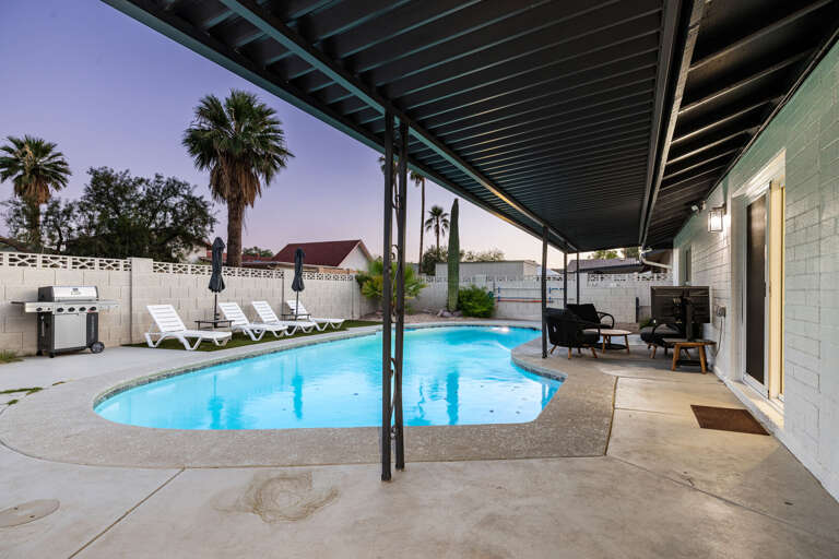 Spacious backyard retreat featuring a sparkling pool, covered lounge area, and resort-style ambiance.