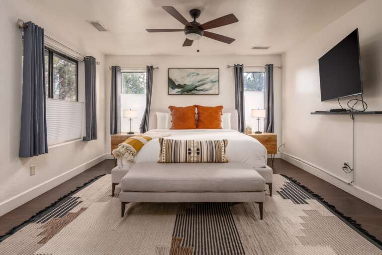 Retreat to the spacious primary suite, complete with a king bed, cozy seating, and a wall-mounted TV for relaxing nights in.