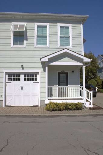 White Wooden Vacation Rental With Porch And Garage Under Blue Sky White Wooden Vacation Rental With Porch And Garage Under Blue Sky