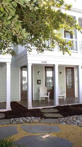 White Wooden Building With Walkway, Windows, And Chair
