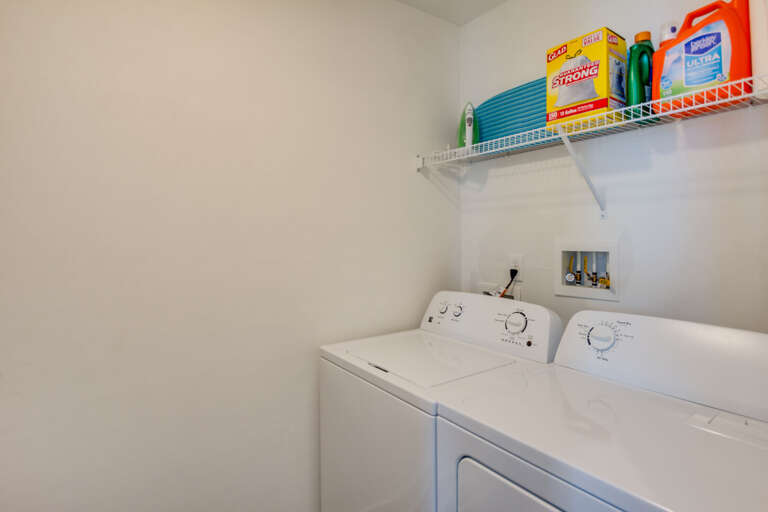 Laundry room with iron, ironing board, detergent, broom and vacuum. Laundry room with iron, ironing board, detergent, broom and vacuum.