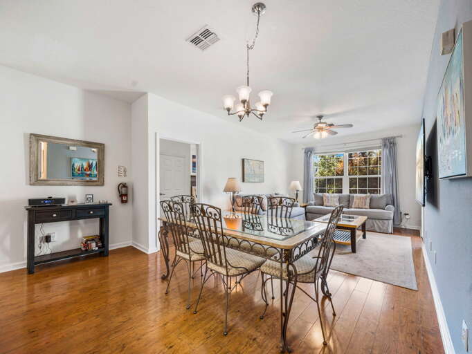 Dining Area With Metal Chairs, Wooden Floor, Ceiling Lights, And A Window View