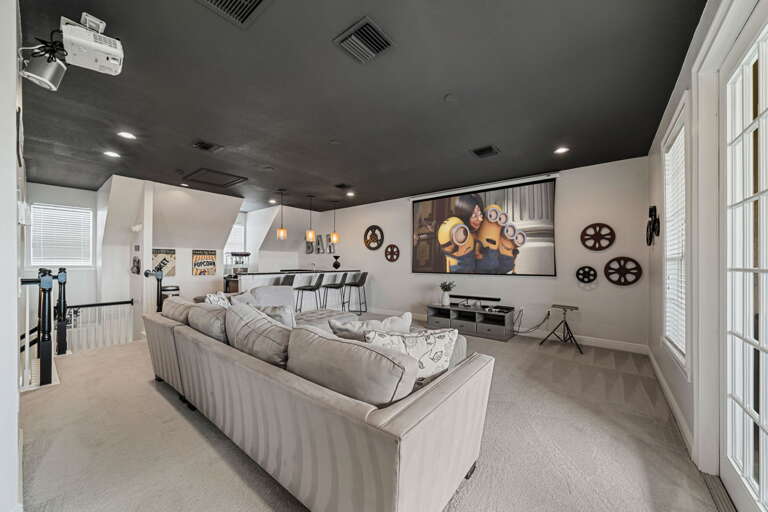 Spacious Living Space With Plush Sofas, Geometric Wall Decor, And A Minimalist Kitchen Area
