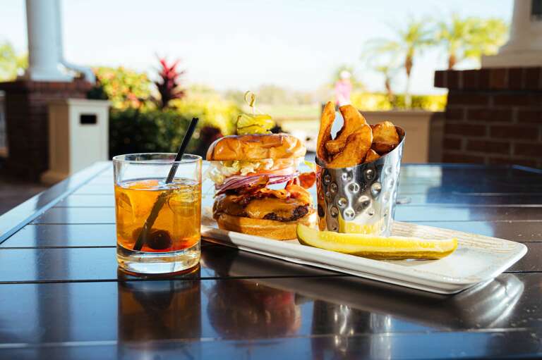 Burger And Beverage Beside Basket Of Crispy Chips