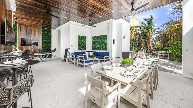Patio View Of A Vacation Rental With Dining Setup Surrounded By Serene Greenery