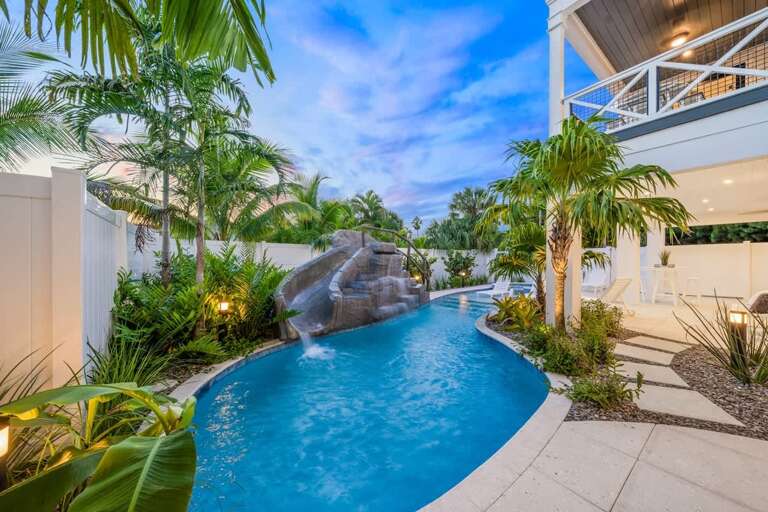 Tropical Pool With Slide And Scenic Sky At Dusk