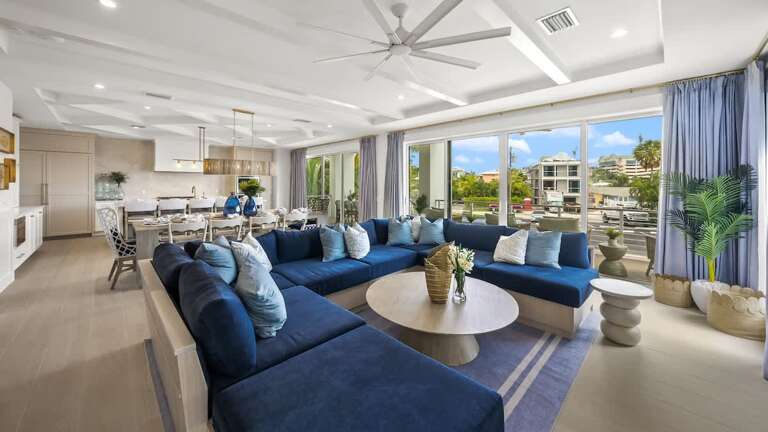 Spacious Living Area With Blue Sofas, Open Kitchen, Leading To Balcony View