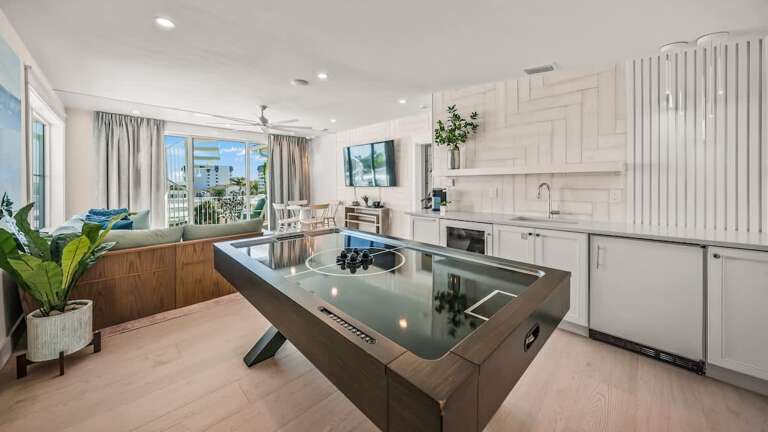 Spacious Vacation Rental Kitchen With Pool Table, Plants, And Balcony View