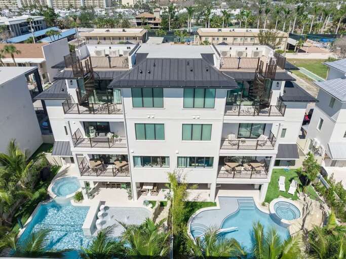 Aerial View Of A Gleaming, Grey Vacation Rental Surrounded By Swaying Palms And Serene Swimming Pool