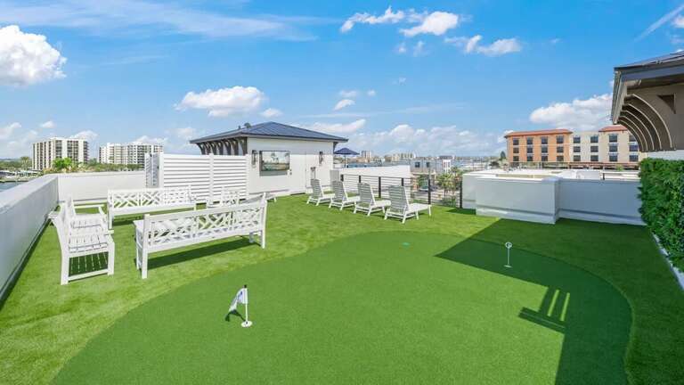 Rooftop Green Grass Area With White Benches And Distant Cityscape