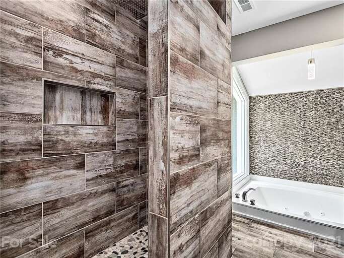 Enjoy a sunken jet tub, walk-in rain shower, double vanity and beautifully-textured tiles.