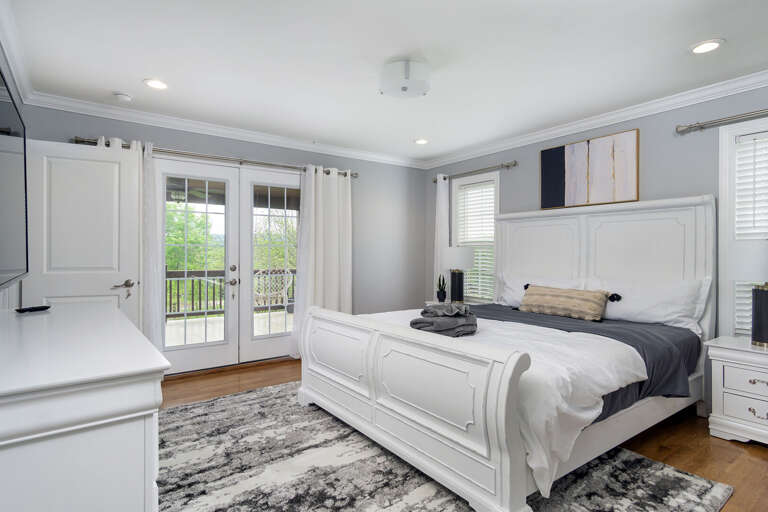The primary bedroom has french doors that open to the expansive upper deck, complete with hanging macrame seats and rattan furniture.