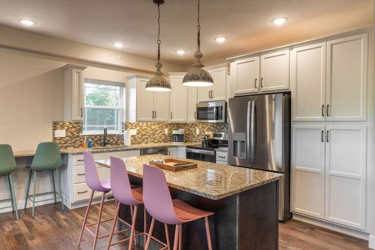 Spacious Kitchen With Island, Pendant Lights, And Bar Stools