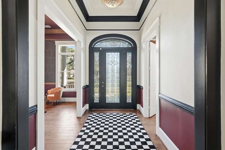 Entryway With Arched Glass Door And Checkered Rug