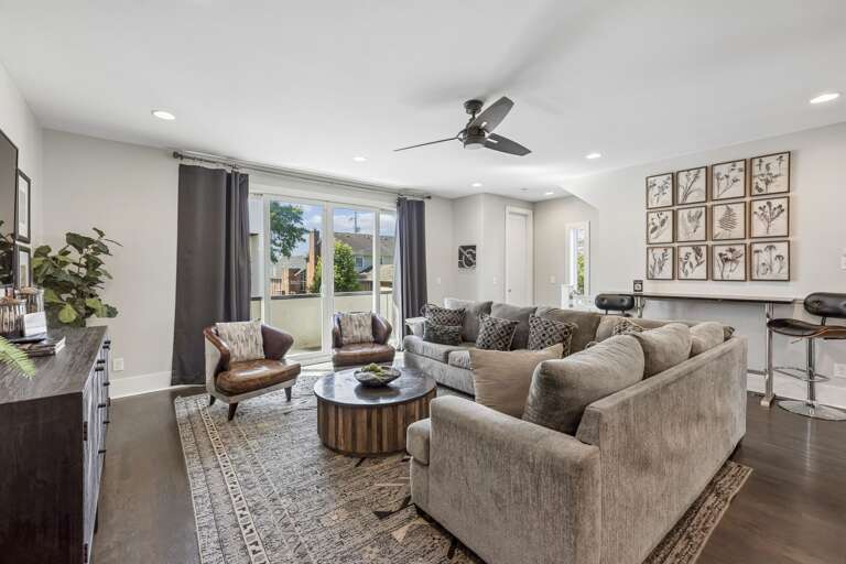 Spacious sectional and accent chairs provide room for the whole group to relax - Natural light pours through large windows, highlighting the clean, modern design - Botanical wall art and bar seating blend comfort with visual interest and function