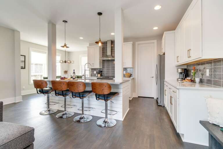 - Kitchen with sleek white cabinetry, quartz counters, &amp; stainless steel appliances - Spacious island with seating for four &amp; pendant lighting ideal for gathering &amp; dining - Subway tile backsplash &amp; open layout create a modern, welcoming c