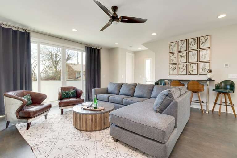 - Spacious sectional and accent chairs provide room for the whole group to relax - Natural light pours through large windows, highlighting the clean, modern design - Botanical wall art and bar seating blend comfort with visual interest and function