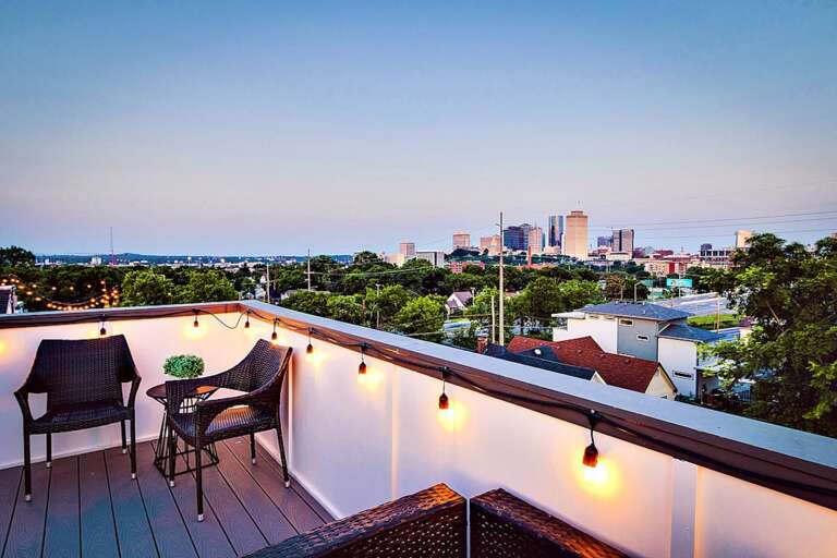 - Cozy rooftop setup with intimate seating for two and magical string lights overhead - Stylish views of the city skyline make this the perfect spot for golden hour drinks - Unwind in the evening breeze with your favorite wine and the lights of downtown