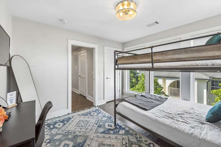 Queen over Queen bunk framed by oversized windows &amp; natural light - Soft layered bedding with patterned pillows create a cozy and inviting sleep space - Easy access to hallway &amp; shared areas makes this room perfect for families or groups