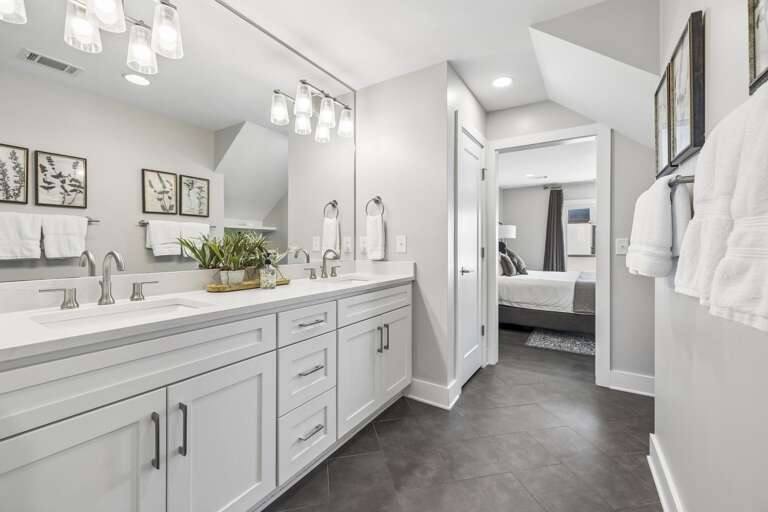 Sleek countertop design with brushed nickel faucet and crisp white quartz surface - Twin faux succulents in rustic pots bring a fresh, natural touch to the bathroom décor - Wood tray base adds texture and warmth to the modern vanity arrangement
