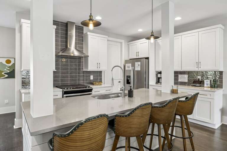 Kitchen with sleek white cabinetry, quartz counters, &amp; stainless steel appliances - Spacious island with seating for four &amp; pendant lighting ideal for gathering &amp; dining - Subway tile backsplash &amp; open layout create a modern, welcoming cul
