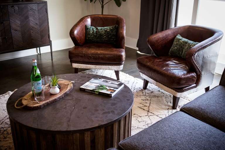- Rich leather club chairs paired with a rustic wood coffee table create an inviting nook - Decorative tray with sparkling water &amp; greenery adds a polished, welcoming touch - Layered textures &amp; industrial modern vibes make this a perfect spot to u
