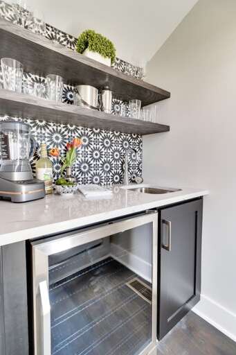 - Chic black and white backsplash adds personality to this sleek mini bar space - Includes a wine fridge, blender, and prep sink for quick drinks or smoothies - Clean countertops and fresh tulips create a polished, welcoming touch