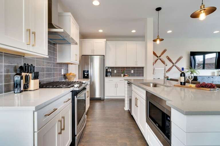 - Full gourmet setup with stainless steel appliances, gas range, and large center island - Chic pendant lights, neutral tile backsplash, and extra counter space for easy prep - Wine and snack board welcome you into this stylish, functional culinary space