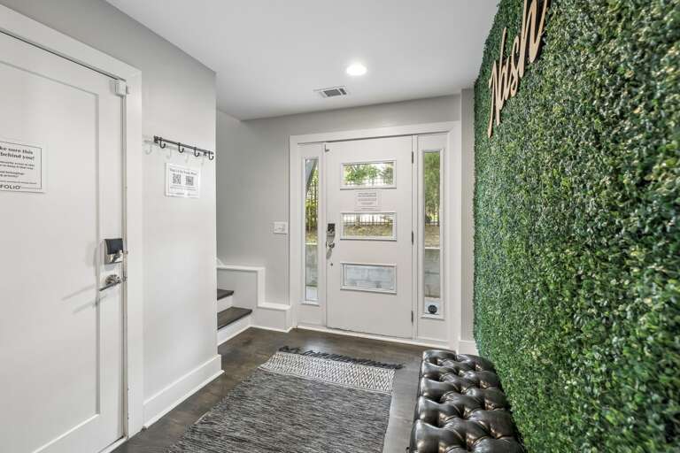 Eye catching artificial green wall brings a vibrant pop of nature inspired style indoors - Paired with a tufted leather bench for a cozy spot to sit, drop bags, or snap a photo - Perfect Instagram worthy moment that adds flair to the hallway or entryway