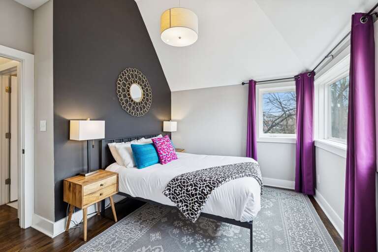 - Wake up to tree lined views &amp; bold purple drapes that frame the sunlight perfectly - Soft pillows, clean lines, &amp; a comfy bed make this space equal parts stylish &amp; soothing - Whether it’s morning light or afternoon naps, this corner is built