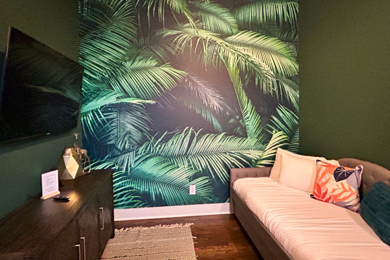 - Escape to your own indoor jungle with bold palm prints and deep green tones - Lounge out on the comfy daybed, catch a movie, or just soak in the chill vibes - With cozy textures and playful decor, this space is made for laid back moments