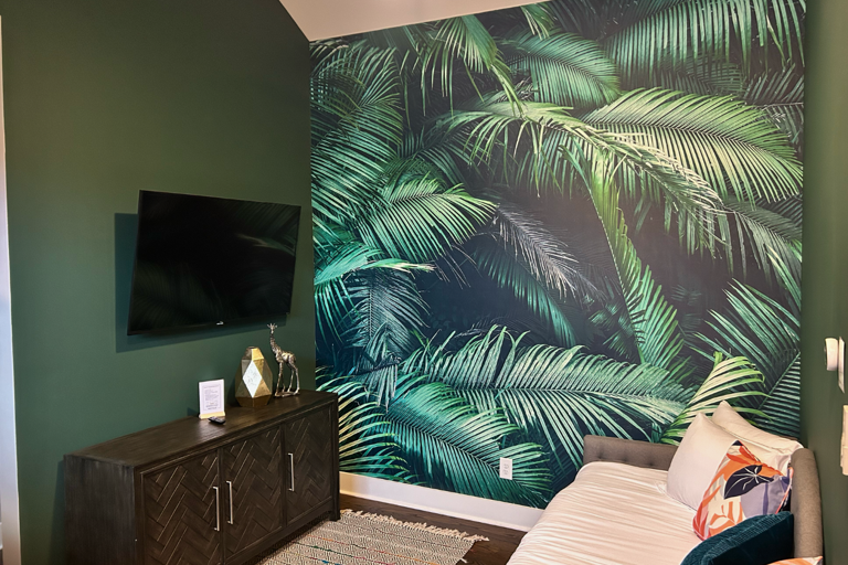 - Dive into vacation mode with this style, palm print retreat and cozy daybed - Stream your favorites or take a nap, this vibrant space is all about laid back vibes - With bold greens, soft pillows, and a touch of whimsy, it’s your own indoor escape