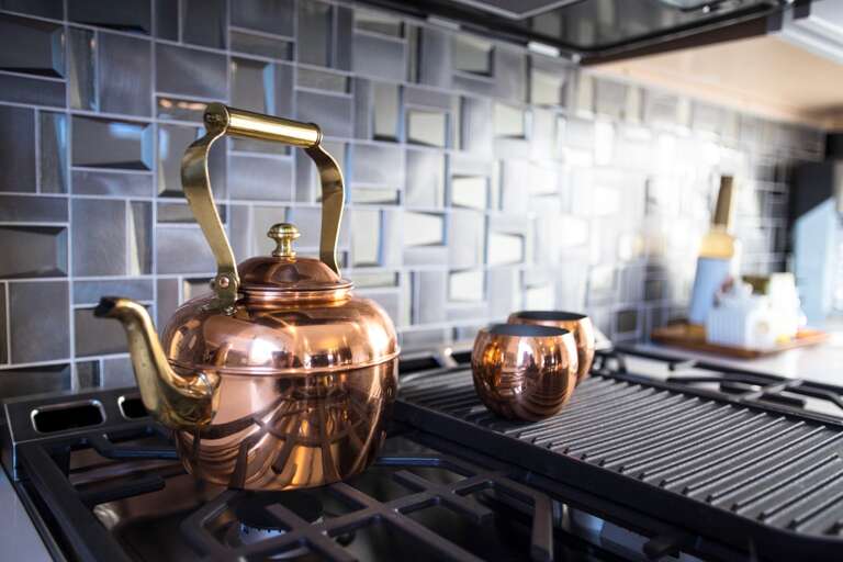 - Fire up flavor with this sleek gas range and standout copper kettle setup - Stylish details like the geometric backsplash and gold accents add major flair - Whether it’s tea time or dinner prep, this corner brings the heat in style