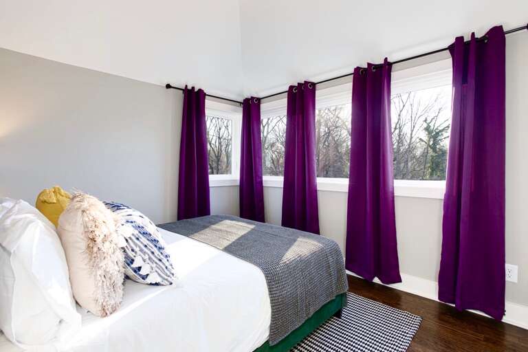 - Wake up to tree lined views &amp; bold purple drapes that frame the sunlight perfectly - Soft pillows, clean lines, &amp; a comfy bed make this space equal parts stylish &amp; soothing - Whether it’s morning light or afternoon naps, this corner is built