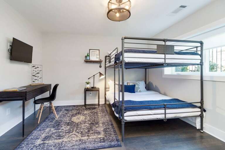 - Queen over queen bunk bed, styled in fresh white &amp; navy tones - Work ready space with sleek desk, mounted TV, &amp; soft rug underfoot for added comfort - Bright window, framed art, &amp; minimalist lighting create a peaceful vibe for any guest