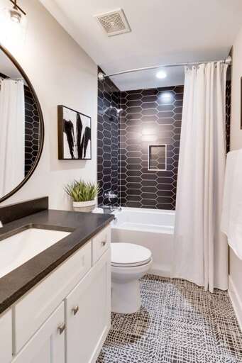 - Sleek black tile and modern design make this bathroom feel fresh and stylish - Mix of bold contrast and soft touches, perfect for a calming soak or quick refresh - Clean lines, artful accents, and a layout built for comfort and function  