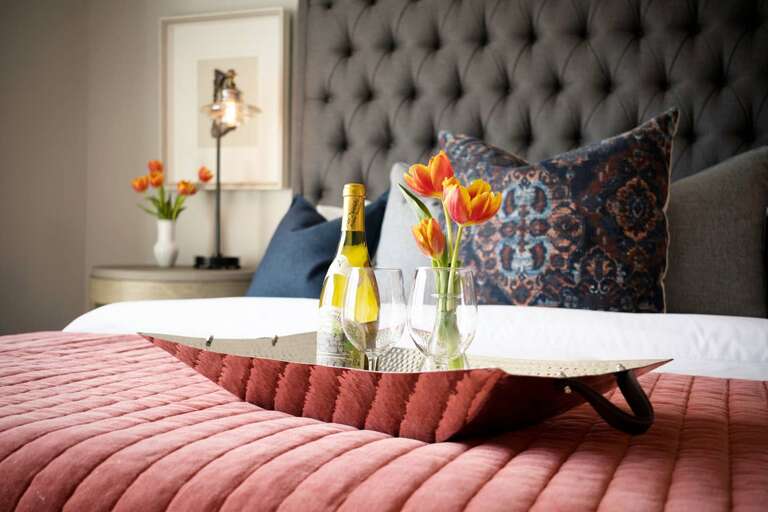 - Tufted headboard and patterned pillows create a warm, upscale vibe for restful nights - Decorative tray with champagne and tulips sets the mood for a relaxing stay - Designer textures and soft lighting add elegance and charm to this inviting space