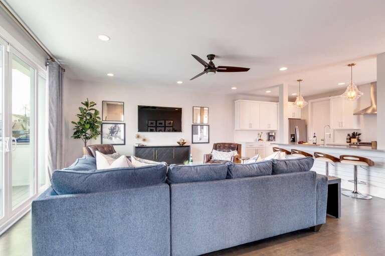 - Bright and airy space featuring a large sectional facing a sleek entertainment center - Blends seamlessly into the modern kitchen with island seating and pendant lighting - Perfect for movie nights, group gatherings, or relaxing with family and friends