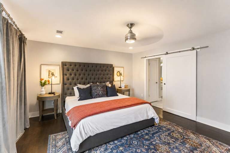 Wake up in the master suite — king bed with a charcoal tufted headboard, barn door, and private balcony doors to greet the morning.