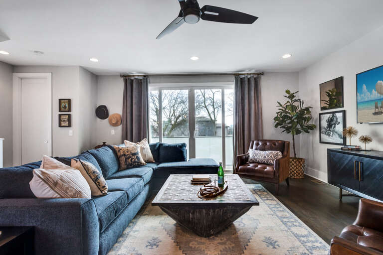 - Deep blue sectional with plush pillows invites lounging in front of the flat screen TV - Thoughtfully styled with leather armchairs, unique artwork, and layered décor - Large window offers natural light and tree filled views for a relaxed, airy feel