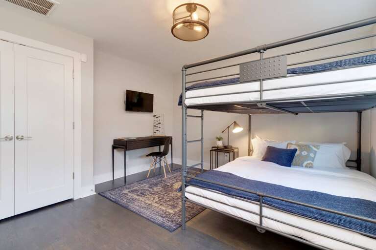 - Second view reveals more of the room’s clean layout and double door closet - Minimalist desk, modern light fixture, and pops of color elevate the entire space - Perfect sleep and study room setup for kids, teens, or flexible group stays