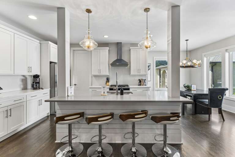 Gather around the quartz island — bar seating for four, gas range behind, and everything a group of ten needs to cook together.