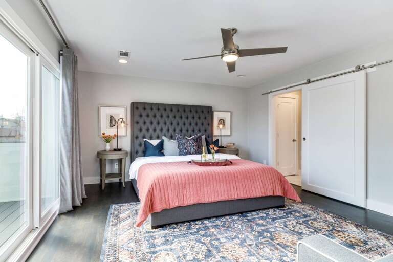 - Comfortable King bed with tufted headboard, vibrant coral bedding, and designer pillows - Sliding barn door leads to a private bath, adding farmhouse style charm - Large rug, curated artwork, and soft lighting create a stylish yet cozy retreat