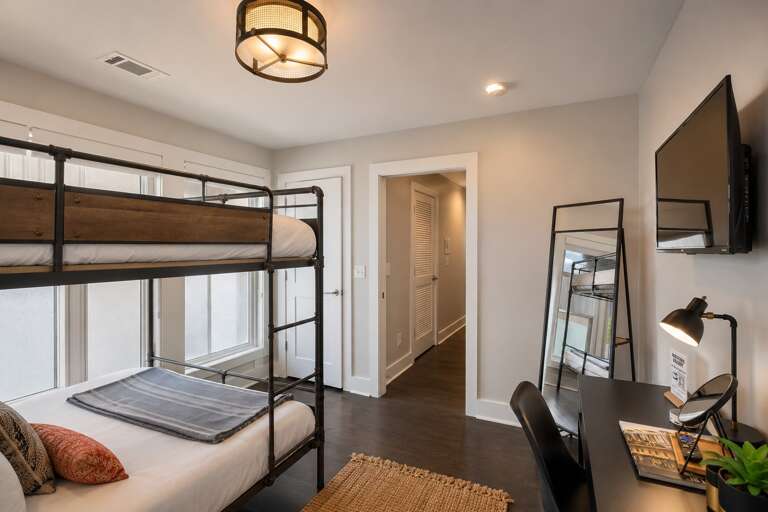 Take the lower bunk and you still get a real bed — queen-size mattress, layered bedding, and enough space that it doesn't feel like a consolation prize.